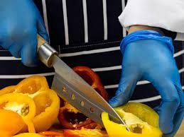 Chef wearing blue gloves and chopping vegetables